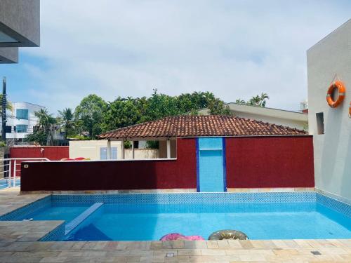 a swimming pool with a house with a tile roof at Hotel Rosa da Ilha Guaruja - Perto do Mar com piscina in Guarujá