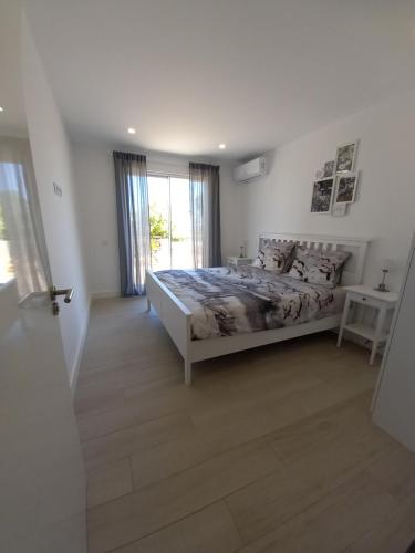 Villa Girassol met zwembad في ألكانتيريا: غرفة نوم بيضاء بها سرير ونافذة