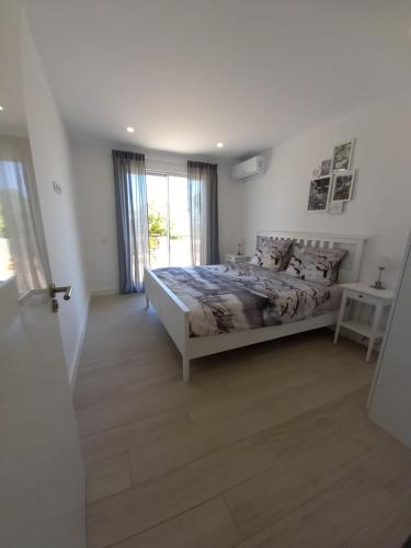 a white bedroom with a bed and a window at Villa Girassol met zwembad in Alcantarilha