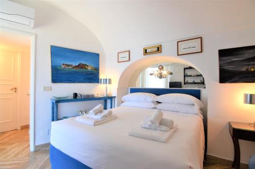 um quarto com uma grande cama branca e 2 toalhas em Villa Castello Apartments em Capri