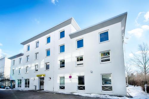 a white building with blue windows at B&B Hotel München-Putzbrunn in Putzbrunn