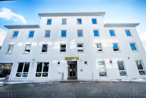 a white building with blue windows on a street at B&B Hotel München-Putzbrunn in Putzbrunn