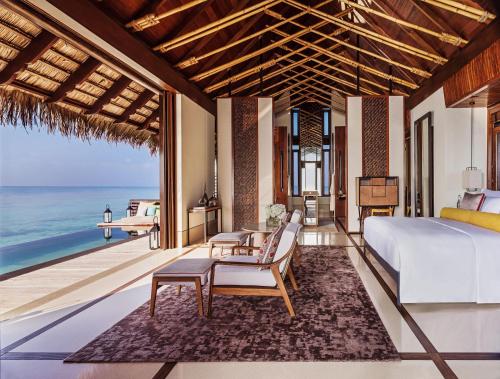 a bedroom with a bed and a view of the ocean at One&Only Reethi Rah in Reethi Rah