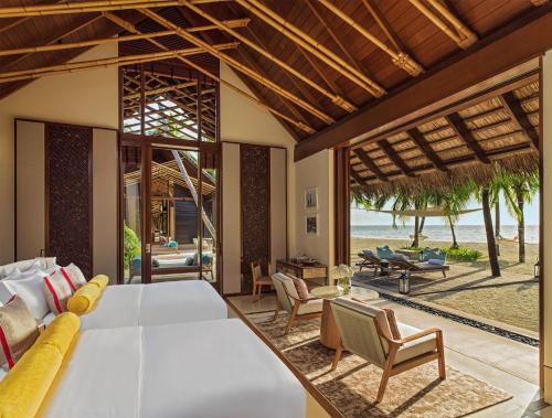 a bedroom with a large bed and a living room at One&Only Reethi Rah in Reethi Rah