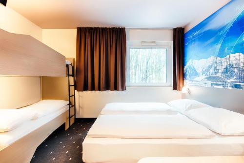a hotel room with two beds and a window at B&B HOTEL München-Airport in Hallbergmoos