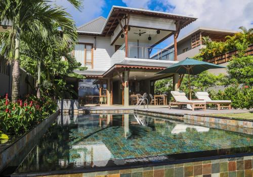 a house with a swimming pool in front of a house at JA Enchanted Waterfront Seychelles in Mahe