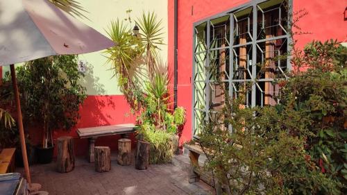 a red building with a bench and some plants at Aji Hostel in Santiago