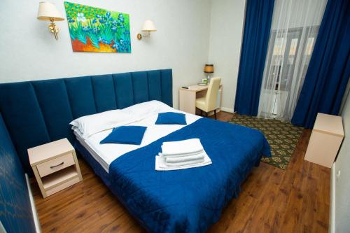 a bedroom with a blue bed with towels on it at Aruna Hotel in Astana
