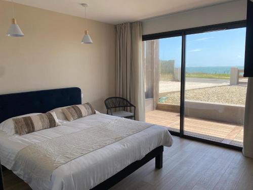 een slaapkamer met een bed en uitzicht op de oceaan bij Hôtel Le Lichen De La Mer in Batz-sur-Mer