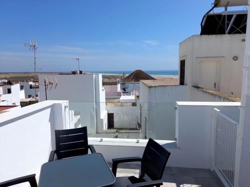 a balcony with two chairs and a table on a building at Casa El Cuartel with private seaview rooftop in Conil de la Frontera