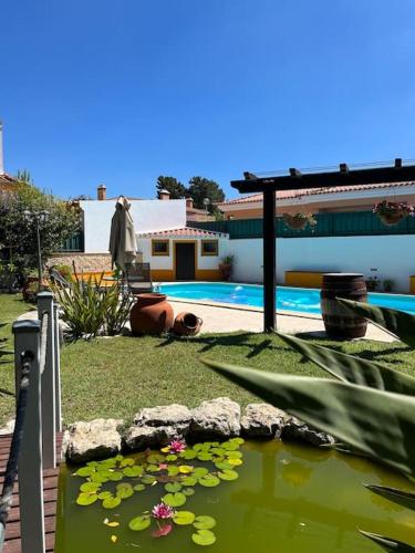a pond with lilies in a yard next to a house at Cafofos da Zeta, Cozy Pool House in Quinta do Conde