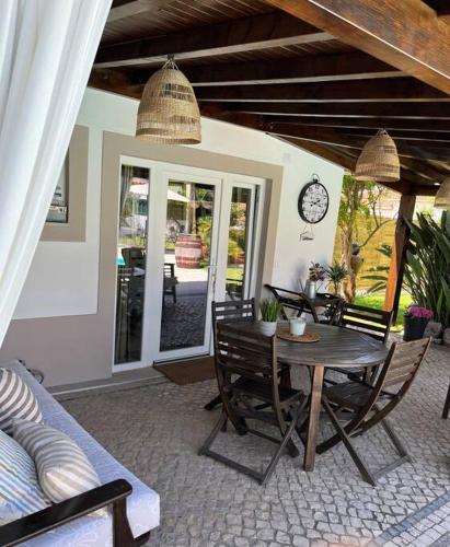 a patio with a table and chairs and a clock at Cafofos da Zeta, Cozy Pool House in Quinta do Conde