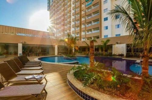 ein Hotel mit einem Pool mit Liegestühlen und einem Gebäude in der Unterkunft Apto do Veloso no Resort in Olímpia