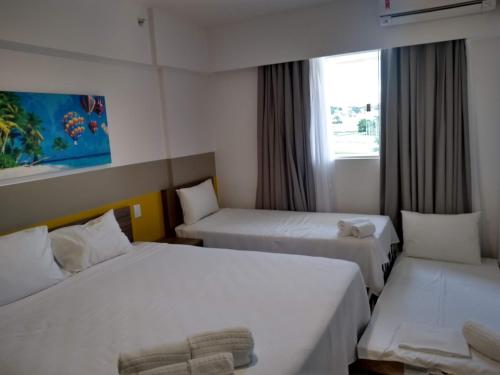 ein Hotelzimmer mit zwei Betten und einem Fenster in der Unterkunft Apto do Veloso no Resort in Olímpia