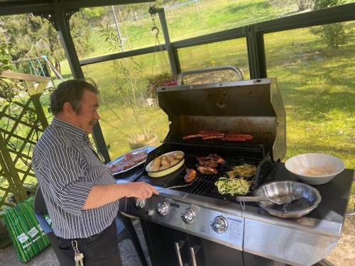 a man is cooking food on a grill at Au Château Saint Blaise in Virignin