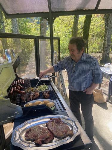 a man standing next to a grill with meat at Au Château Saint Blaise in Virignin