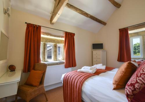 um quarto com uma cama, uma secretária e 2 janelas em TLasses Cottage em Kildwick
