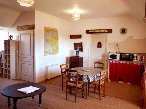 a living room with a table and a kitchen at Les Gîtes du Couvent Alternatif in Camlez