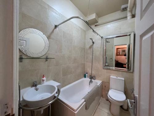 a bathroom with a tub and a sink and a toilet at Comfy Apartments - Finchley Road in London