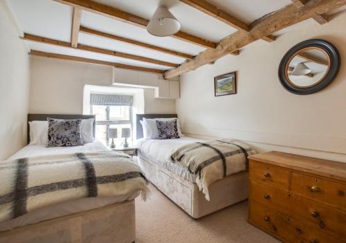 two beds in a room with a mirror and a dresser at Thornsgill Cottage in Askrigg
