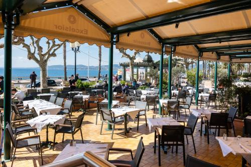 een restaurant met witte tafels en stoelen en de oceaan bij Excelsior in Saint-Raphaël