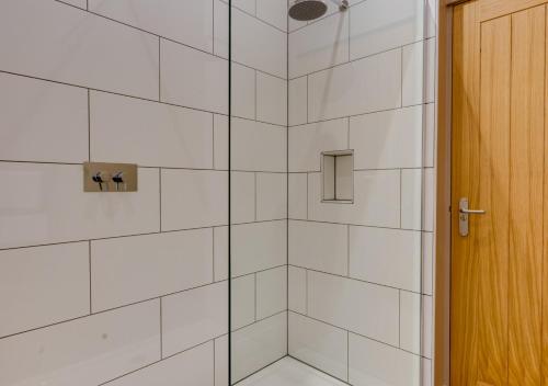 a bathroom with a shower with white tiles at The Stables at The Foldyard in Holme upon Spalding Moor