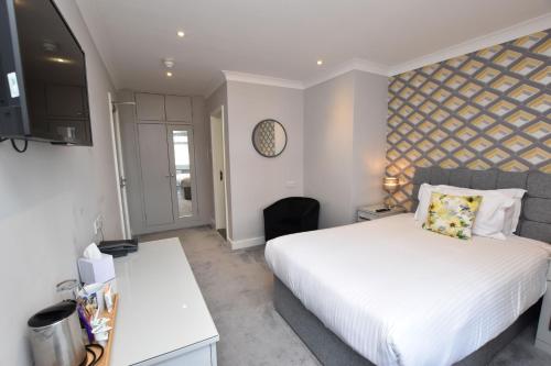 a bedroom with a large white bed and a desk at Kingsway Hotel. in Cleethorpes