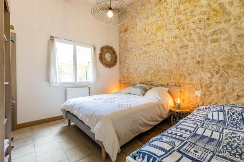 1 dormitorio con cama y pared de piedra en Gite Senguinous 2, en Lesparre-Médoc