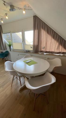 una mesa blanca y sillas en una habitación con ventanas en 'Strandhafer', en Langeoog