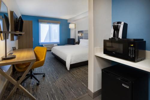 a hotel room with a bed and a desk with a tv at Holiday Inn Express and Suites Tampa I-75 at Bruce B. Downs by IHG in Tampa