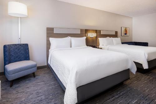 a hotel room with two beds and a chair at Holiday Inn Express and Suites Tampa I-75 at Bruce B. Downs by IHG in Tampa
