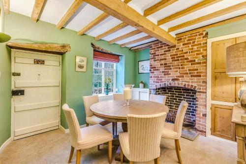 una sala da pranzo con tavolo, sedie e camino in mattoni di Brand Hill Cottage with Hot Tub a Loughborough