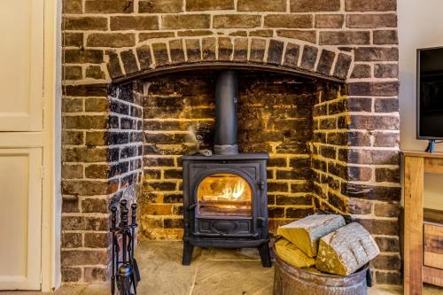 a brick fireplace with a stove in it at Brand Hill Cottage with Hot Tub in Loughborough