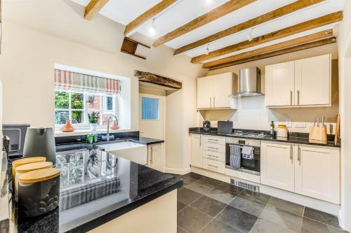 a kitchen with white cabinets and black counter tops at Brand Hill Cottage with Hot Tub in Loughborough