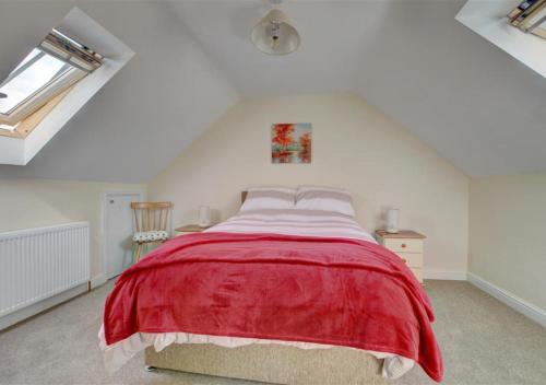 a bedroom with a red bed in a attic at The Old Cow Byre in Lealholm