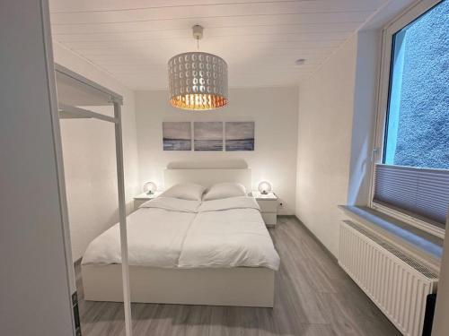 a white bedroom with a bed and a chandelier at Möblierte EG- Wohnung zentral in Herne mit Parkplatz,WLAN und Netflix in Herne