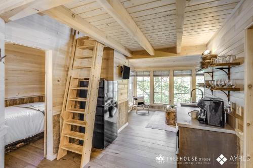 a bedroom with a bed and a kitchen with a ladder at The Blackjack Oak in Treehouse Grove at Norton Creek in Gatlinburg