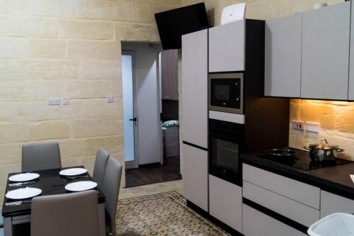 uma cozinha com armários brancos e uma mesa com cadeiras em TOP RATED Traditional Maltese house close to Valletta RARE FIND em Cospicua
