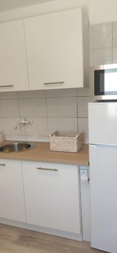 a white kitchen with a sink and a white refrigerator at Appartement 3 pièces avec terrasse au soleil in Le Thoronet
