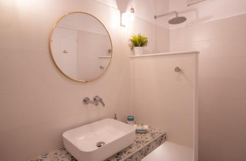 a white bathroom with a sink and a mirror at Ammos Sifnos Village in Platis Yialos Sifnos