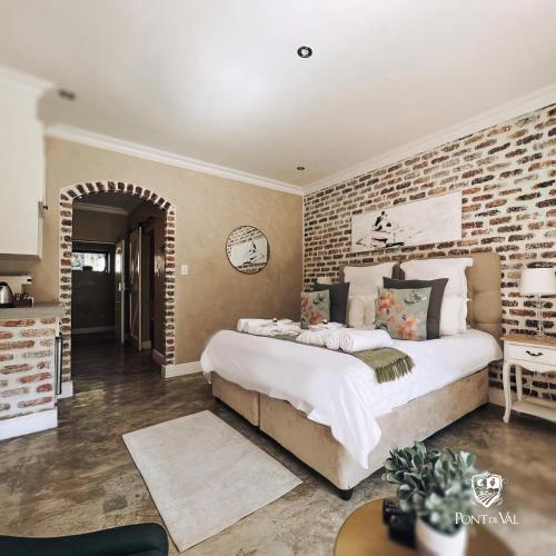 a bedroom with a large bed and a brick wall at Pont de Val Boutique Hotel in Barrage
