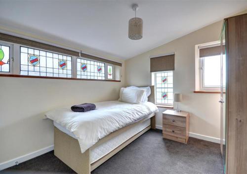 a bedroom with a bed with white sheets and stained glass windows at The Nook in Robin Hood's Bay