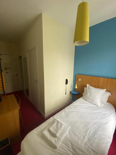a bedroom with a white bed with a light on it at Oscar Hôtel Le Havre Centre in Le Havre