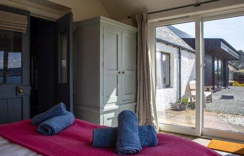a bedroom with a bed with blue towels and a large window at No 6 Oskaig in Raasay