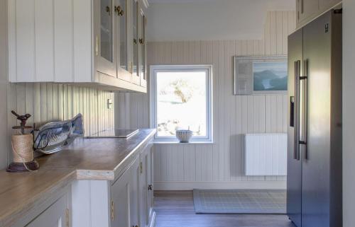 a kitchen with white cabinets and a window at No 6 Oskaig in Raasay