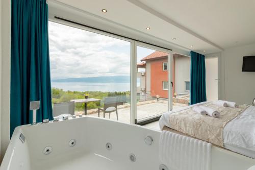 a bathroom with a tub and a bed and a window at Velestovo House in Ohrid