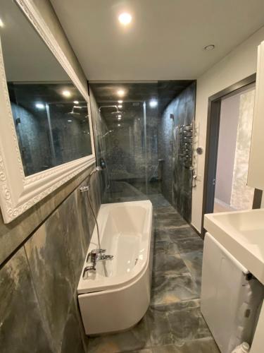 een badkamer met een wastafel en een bad bij City Center Panorama apartment in Kaunas