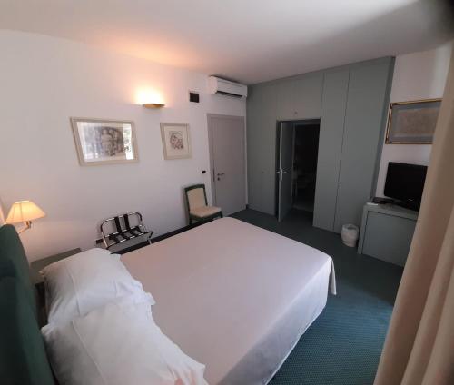 a bedroom with a large white bed and a television at Bellevue San Lorenzo (Adults Only) in Malcesine