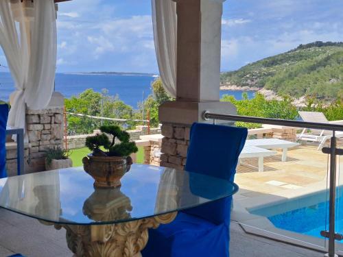 a glass table on a balcony with a view of the ocean at Villa Stone House Poplat in Vela Luka