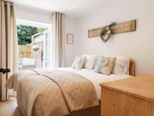 a bedroom with a bed with white sheets and a window at Pantiles in Woodbridge